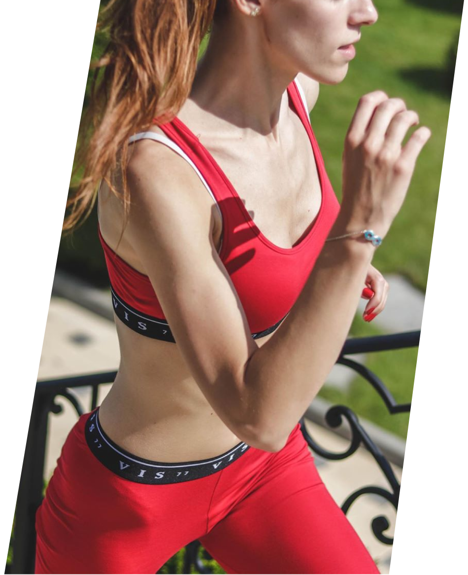 Woman running in coral red sports suit, manufactured in the EU.